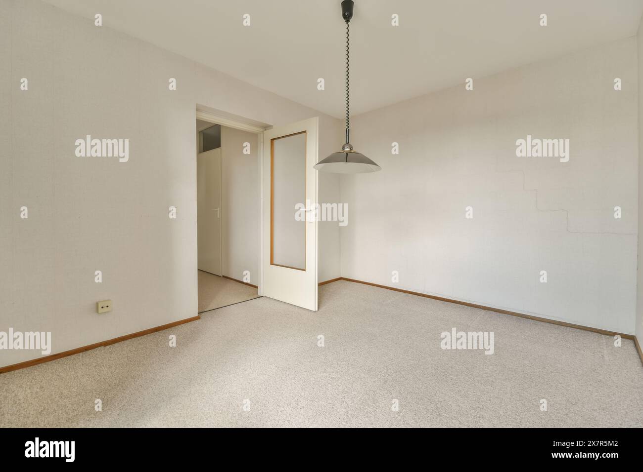 Spaziosa camera vuota con pareti bianche e lampada a sospensione minimalista, ideale per ambienti di design interno Foto Stock