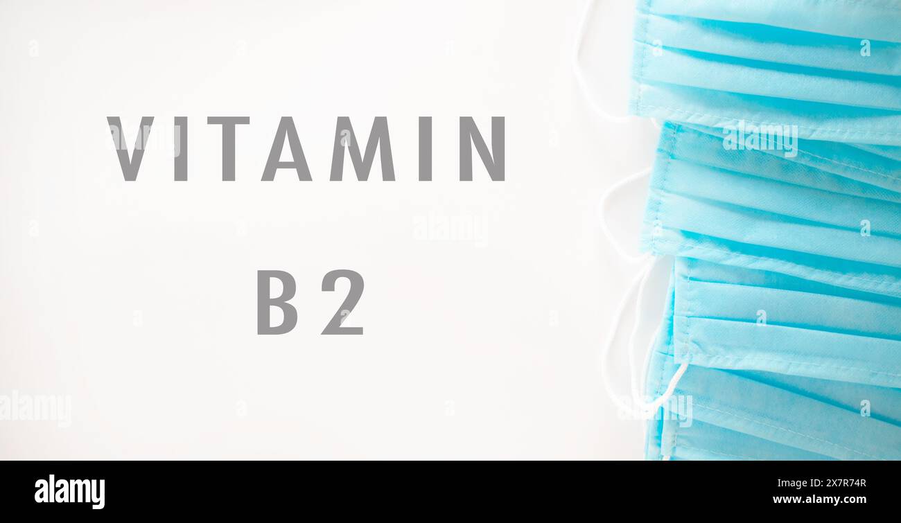 Una pila blu di maschere chirurgiche con la parola vitamina B2 scritta sotto. Concetto di cautela e protezione, in quanto le maschere sono utilizzate in ambiente medico Foto Stock