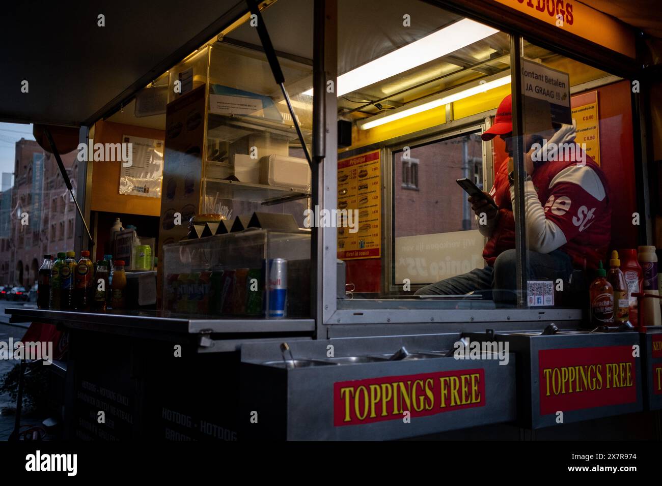 Un food truck hamburger e hotdog dove il venditore consulta i social network sul suo smartphone in Piazza Dam ad Amsterdam, capitale dei Paesi Bassi nell'UE Foto Stock