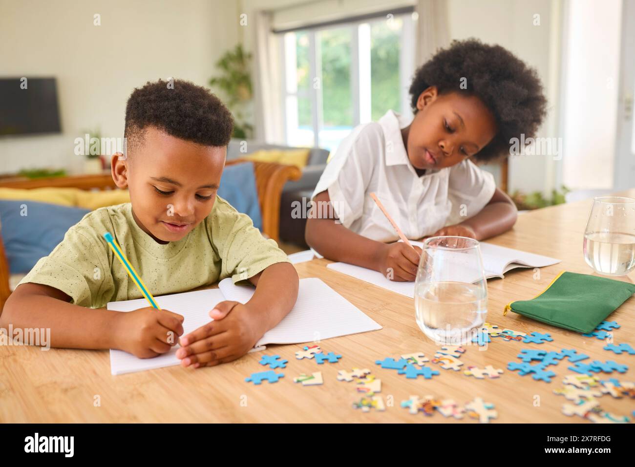 Famiglia al chiuso a casa con bambini che fanno i compiti seduti al tavolo Foto Stock