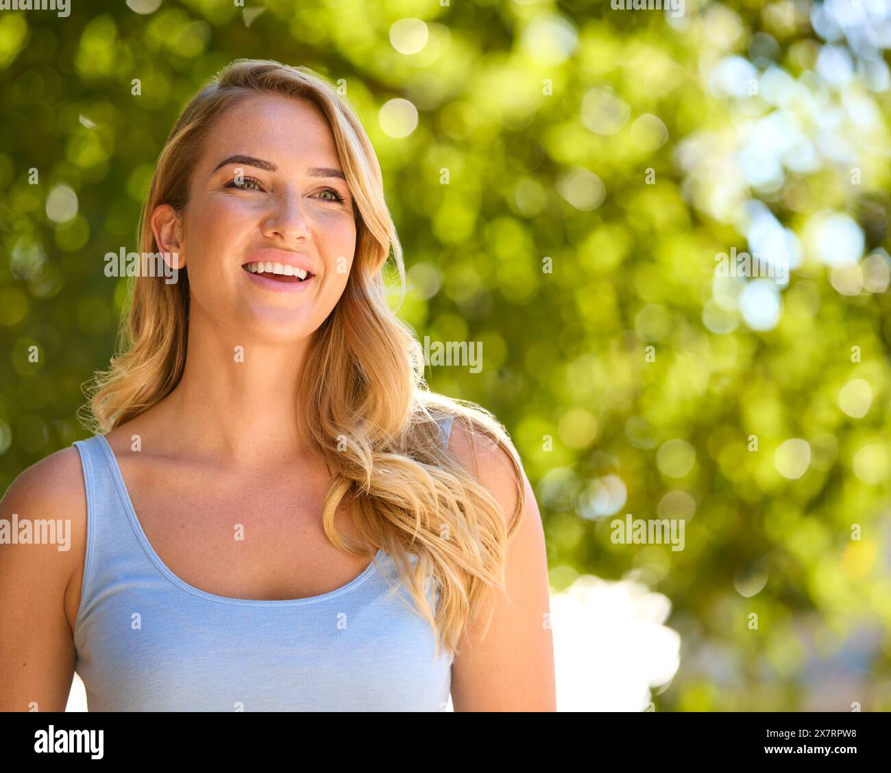 Testa e spalle Ritratto di donna sorridente all'aperto che si rilassa in campagna guardando la fotocamera Foto Stock