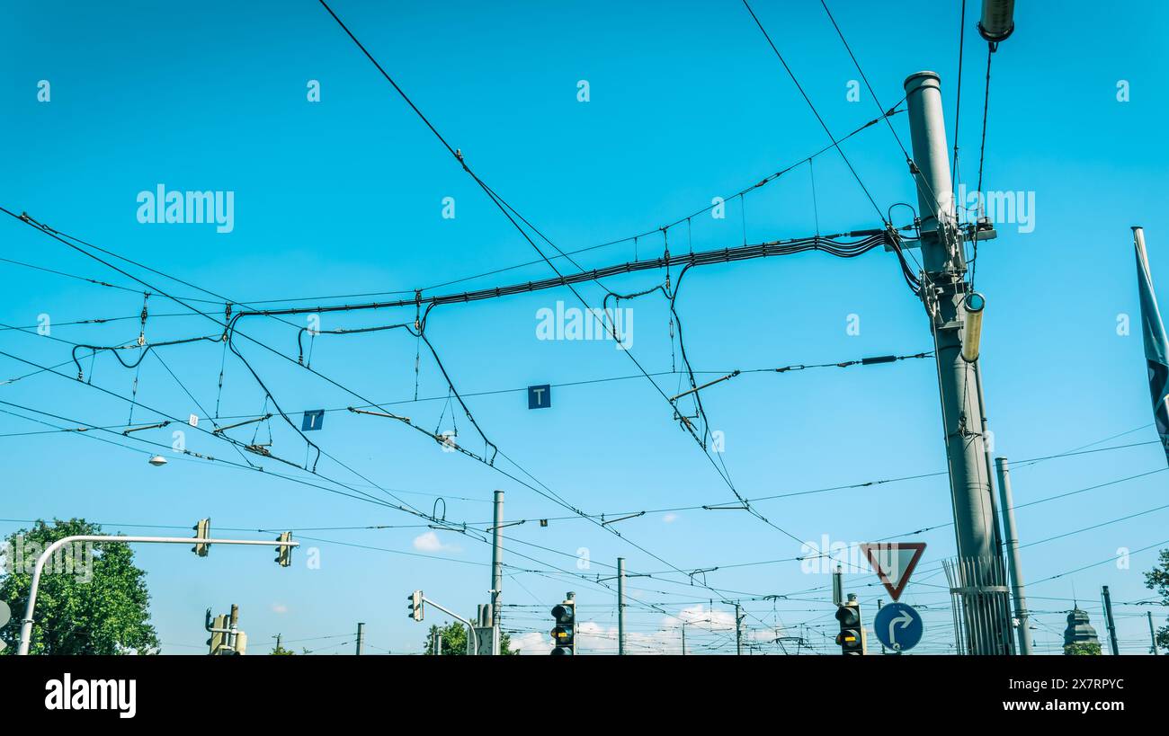 Cablaggio elettrico del tram cittadino e del traffico degli autobus contro il cielo blu Foto Stock