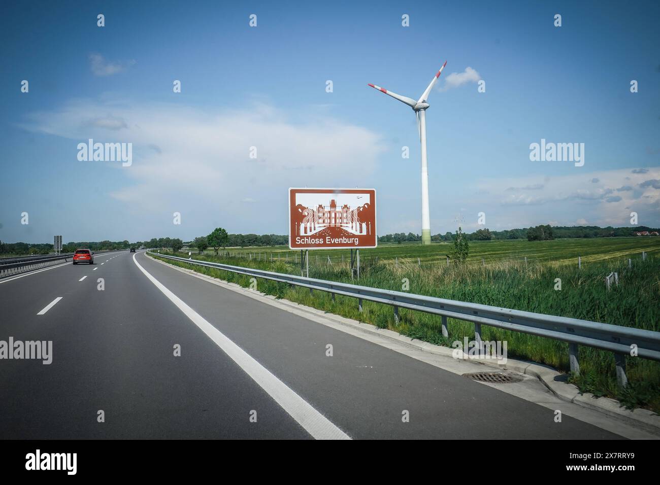 Autobahn, Straßenschild, Schloss Evenburg, Braunes Schild, Windrad, blauer Himmel, Autobahn A31, Verkehrsschild, Auto, Fahrbahn, Leitplanke, Wiesen, Deutschland, Verkehr, Sommer, Wegweiser, Emslandautobahn, Nord-Süd-Verbindung, Schnellstraße, Verkehrsnetz, 241 km da Emden, Bottrop, gebaut 1967-2004, wichtige Route Niedersachsen, Nordrhein-Westfalen, landschaftlich reizvoll, wenig befahren, schnelle Verbindungen, regionale Wirtschaft, Tourist ische Ziele, Schloss, historische Sehenswürdigkeit **** Autobahn, cartello stradale, Schloss Evenburg, cartello marrone, turbina eolica, cielo blu, autostrada A31, segnale stradale Foto Stock