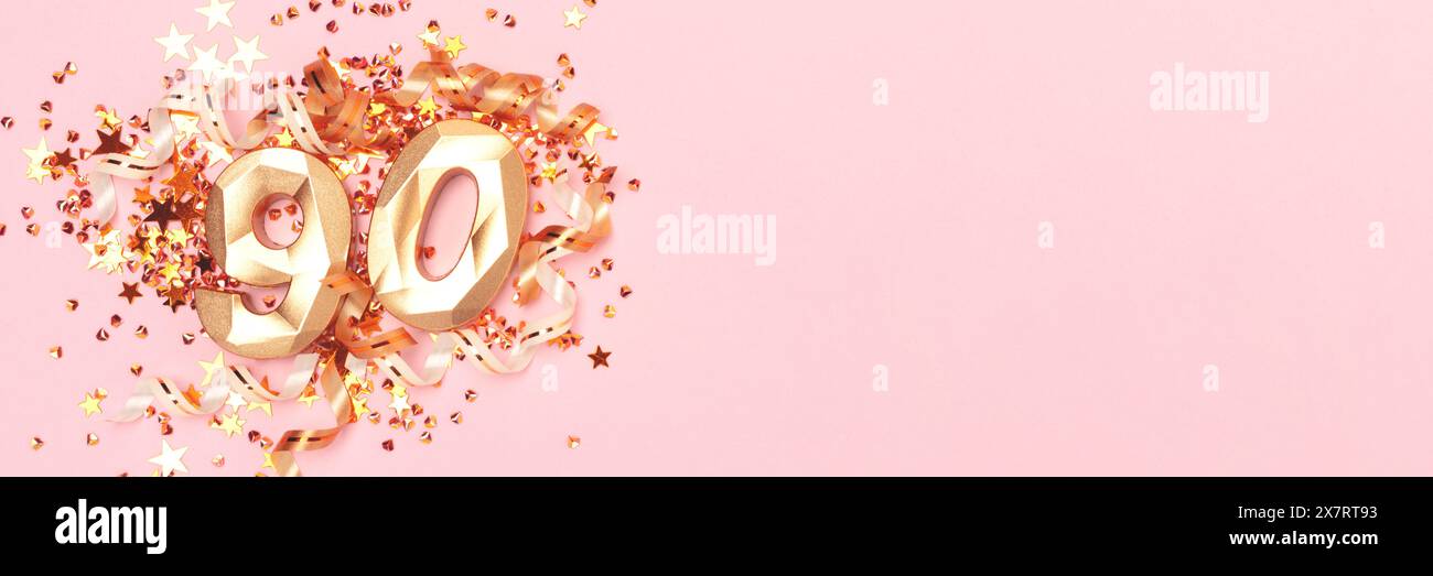 Striscione con numero 90 color oro, nastri e coriandoli con stelle su sfondo rosa. Foto Stock