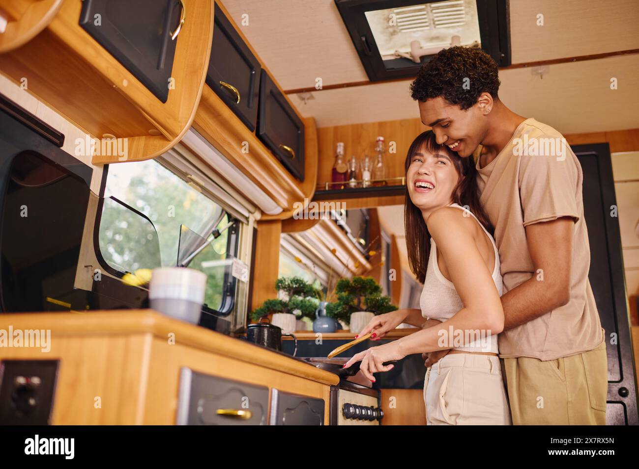 Un uomo e una donna stanno insieme in una cucina accogliente, condividendo un momento di amicizia mentre preparano un pasto. Foto Stock