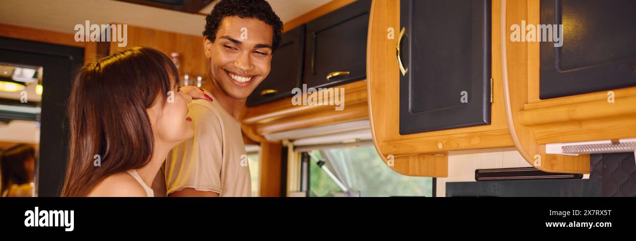 Un uomo e una donna condividono un momento in cucina, circondati dal calore e dall'amore mentre preparano un pasto insieme. Foto Stock