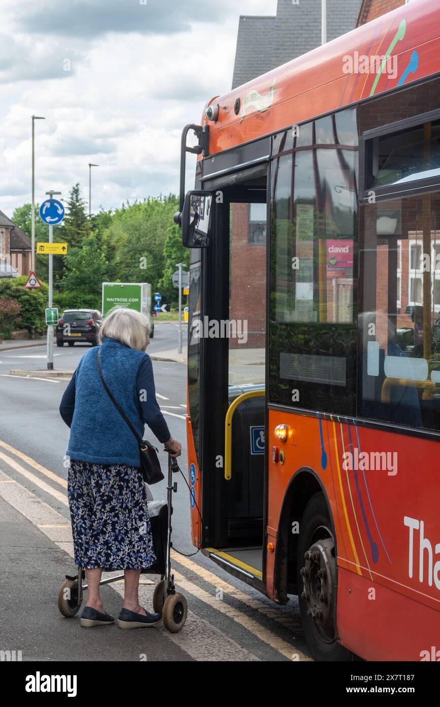 Donna anziana con un camminatore che sale su un autobus in città, Inghilterra, Regno Unito Foto Stock
