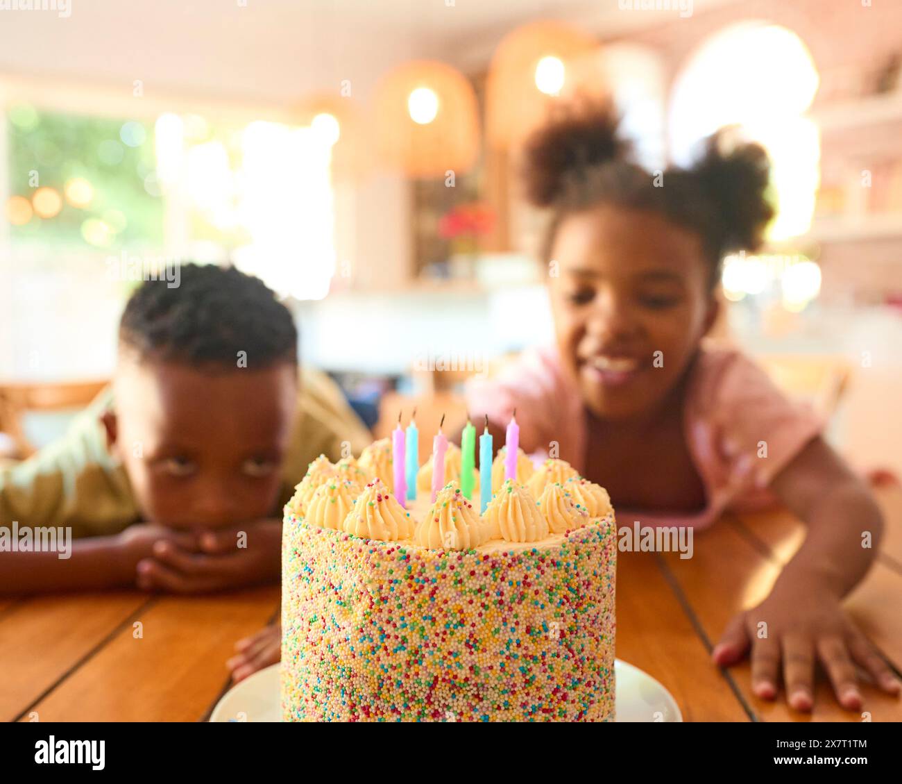 Due bambini che cercano Hungrily alla gustosa torta di compleanno al tavolo per la festa Foto Stock