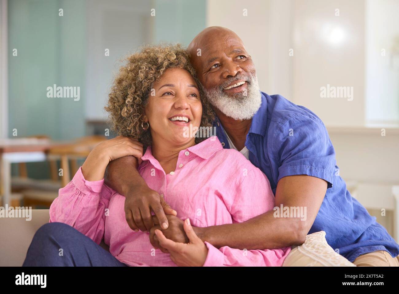 Coppia matura amorevole a casa che abbraccia seduti sul divano nel salotto insieme Foto Stock