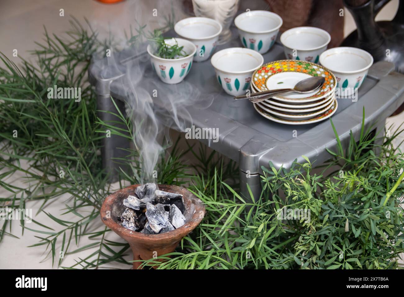 I chicchi di caffè appena tostati, il mortaio e il pestello con jebena e il fumo di incenso creano una tradizionale preparazione per la cerimonia del caffè etiope Foto Stock