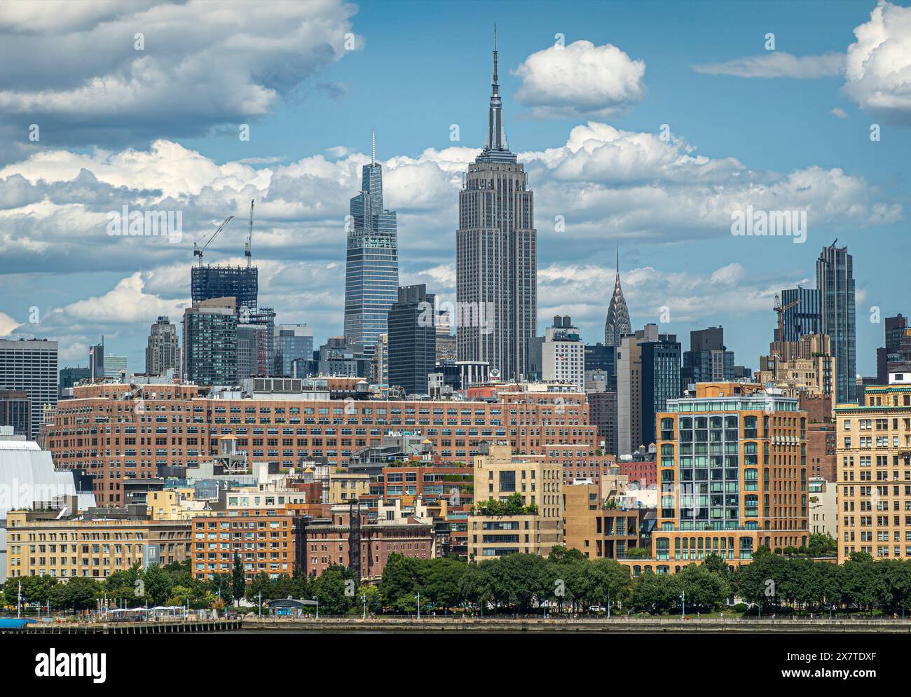 New York, NY, USA - 1 agosto 2023: Un grattacielo Vanderbilt, Empire State e Chrysler visto dal fiume Hudson sotto un paesaggio blu, circondato da Foto Stock