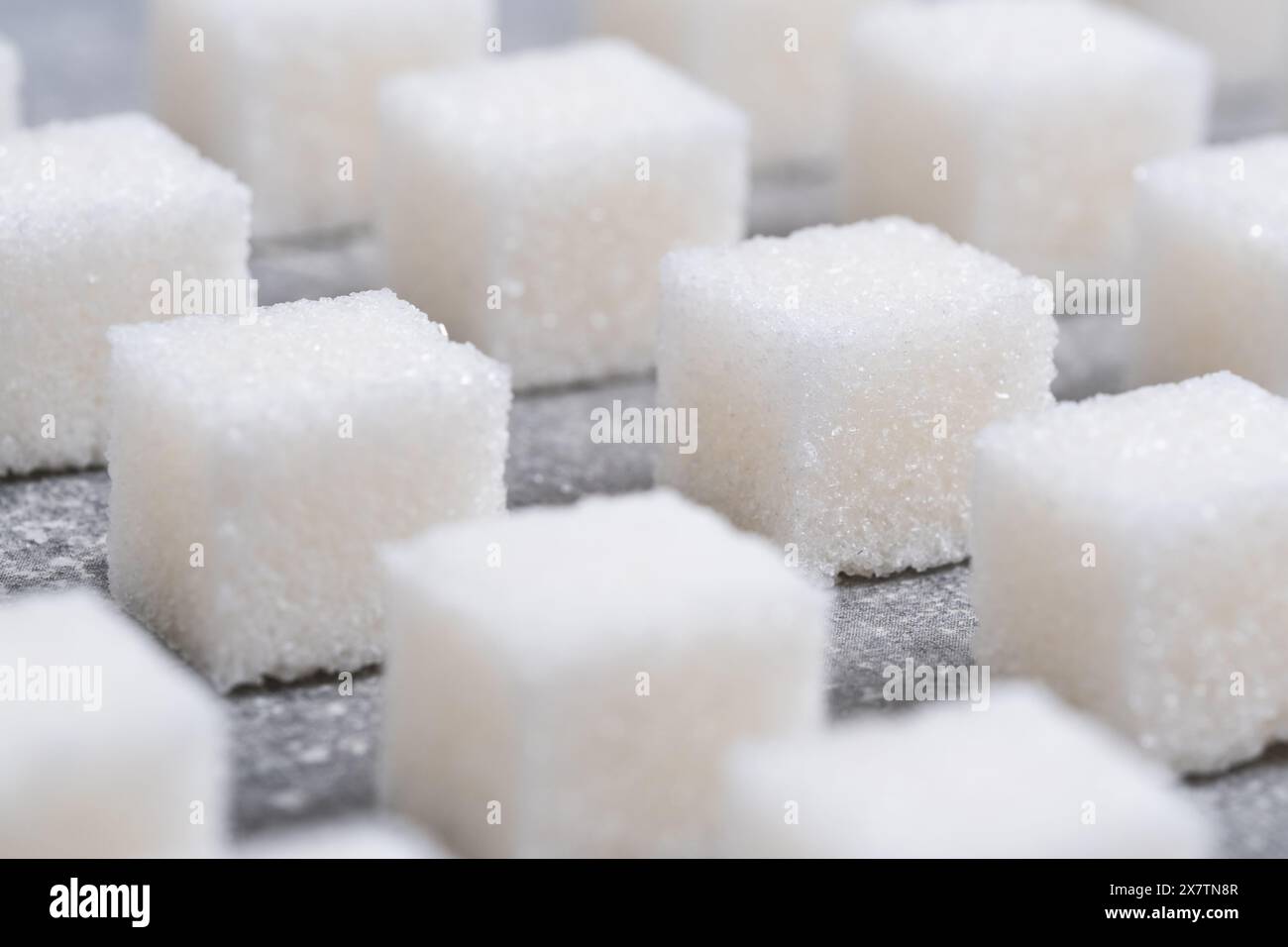 I raffinati cubetti di zucchero sono disposti in linee geometriche chiare Foto Stock