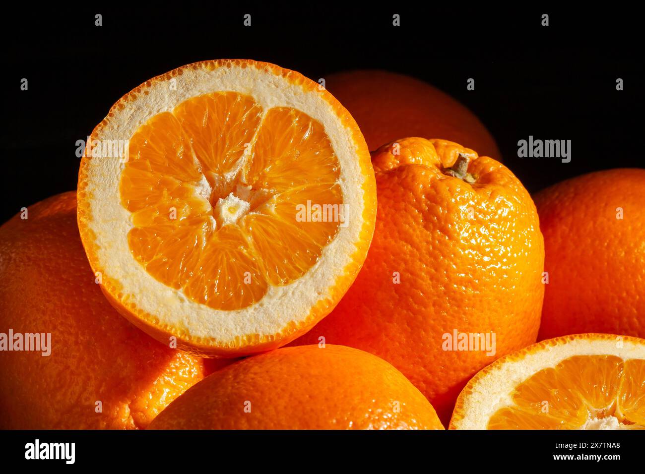 arance bionde ovali calabresi a fette su sfondo nero Foto Stock