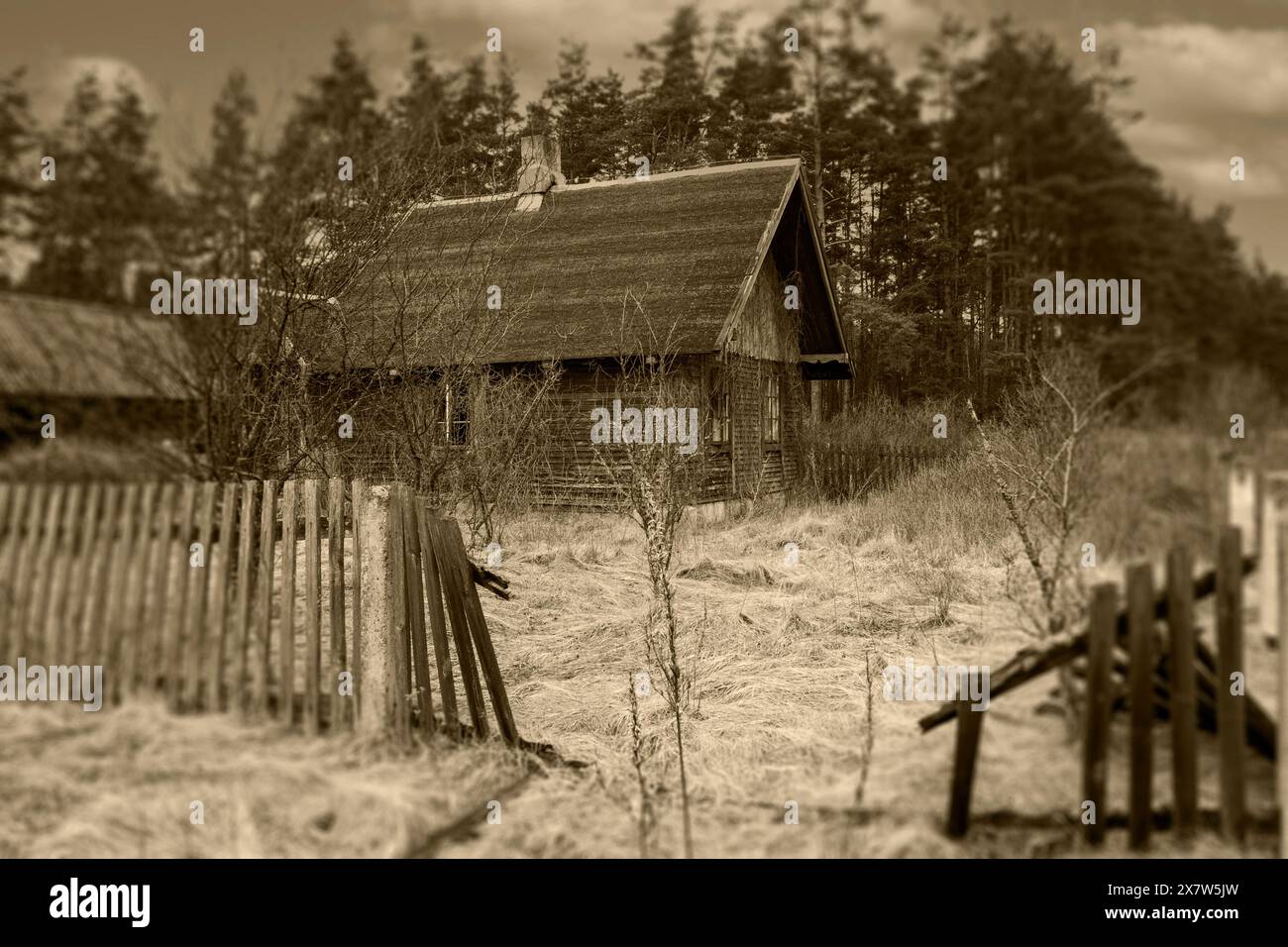Una vecchia casa in legno in una zona remota e una recinzione sbriciolata Foto Stock