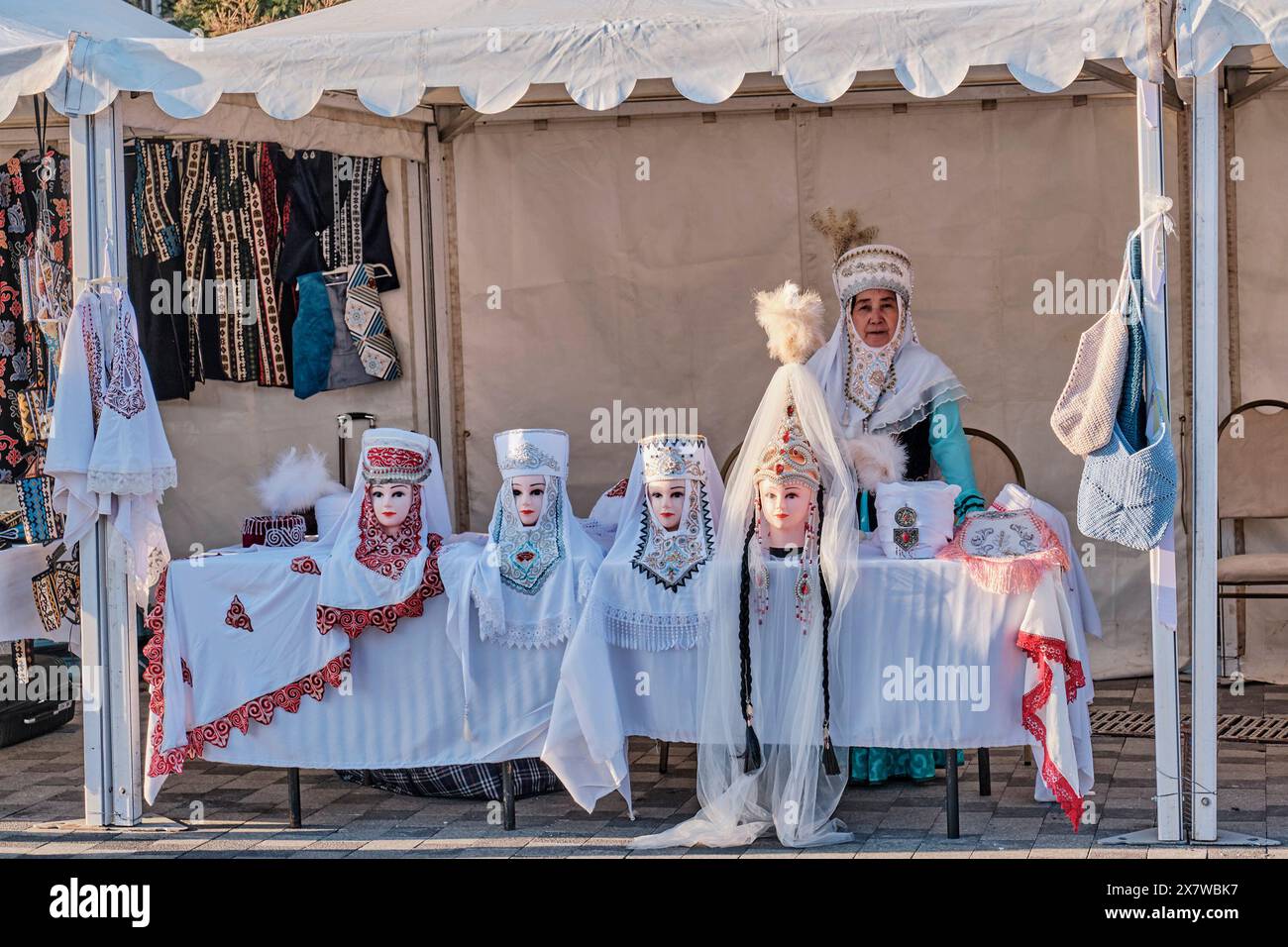 Almaty, Kazakistan - 18 marzo 2024: Copricapi nazionali tradizionali kazaki femminili con ricami sulle teste di manichino. Salesp asiatiche senior Foto Stock