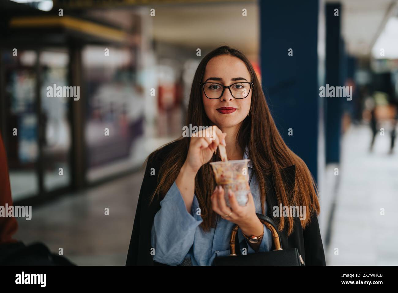 Giovane donna d'affari che mangia uno spuntino sano in un ambiente urbano Foto Stock
