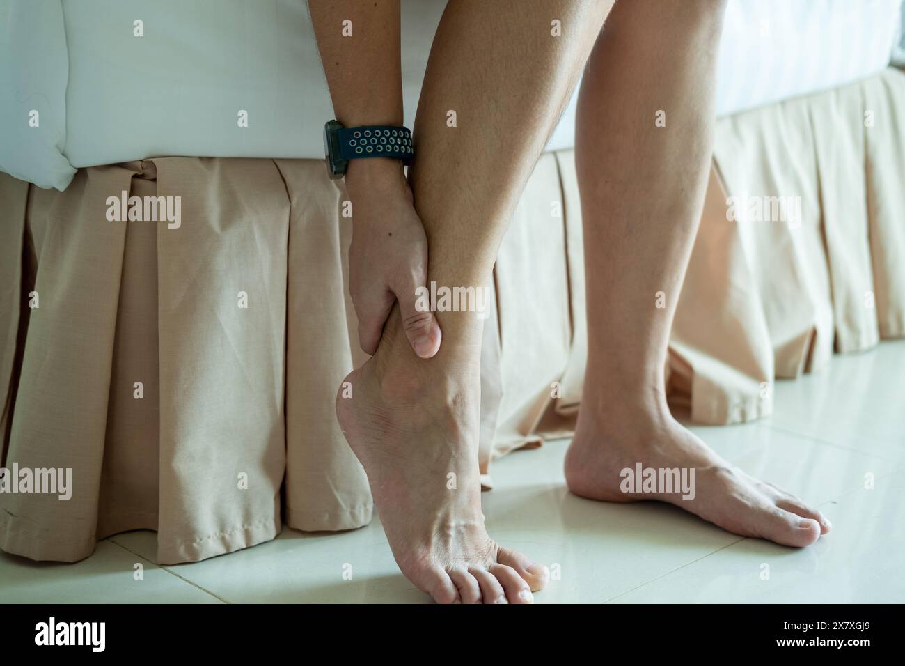 Dolore ai piedi, donna asiatica seduta che sente dolore ai piedi a casa, donna che soffre di dolore ai piedi usando il massaggio delle mani per rilassare i muscoli dalle suole dei piedi Foto Stock