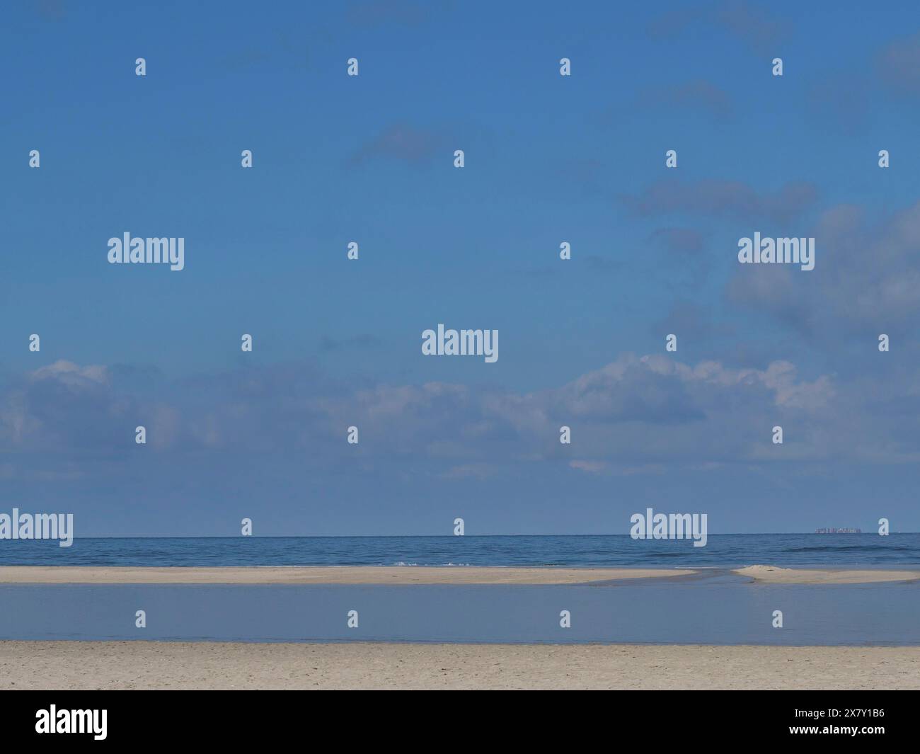 Cielo blu con nuvole sparse su un mare calmo e una spiaggia vuota, cielo ampio su una spiaggia solitaria del Mare del Nord con un cielo blu brillante, Spiekeroog, Germania, E. Foto Stock