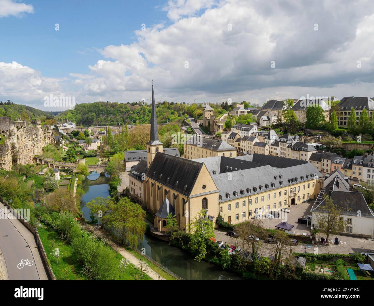 Panorama della città con una chiesa e un fiume, circondato da edifici storici e verdi colline sotto un cielo parzialmente nuvoloso, vecchia chiesa su una piccola riva Foto Stock