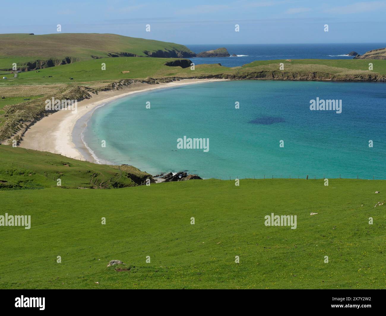 Un pittoresco tratto di costa con colline ondulate, una spiaggia dorata e acque turchesi che si fondono pacificamente nel paesaggio, una spiaggia dorata con g Foto Stock