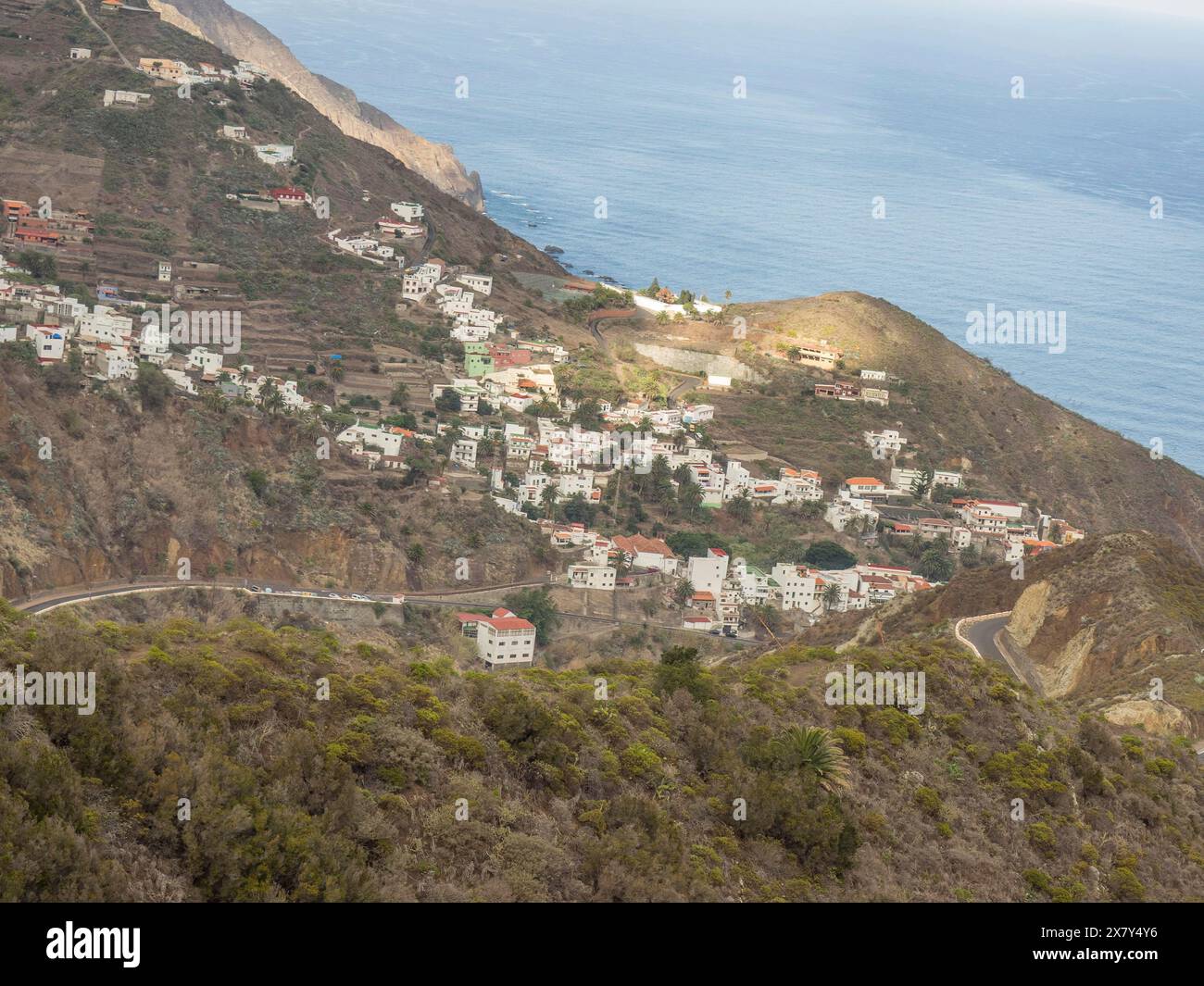 Villaggio sparso sulla costa con vista su montagne e mare, strade tortuose, montagne e valli su un'isola nell'Atlantico con palme Foto Stock