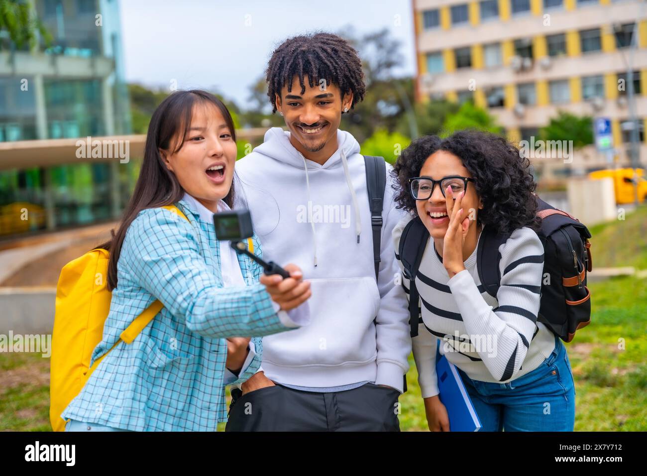 Tre fantastici studenti multietnici che parlano selfie con la fotocamera indossabile e il cavalletto Foto Stock