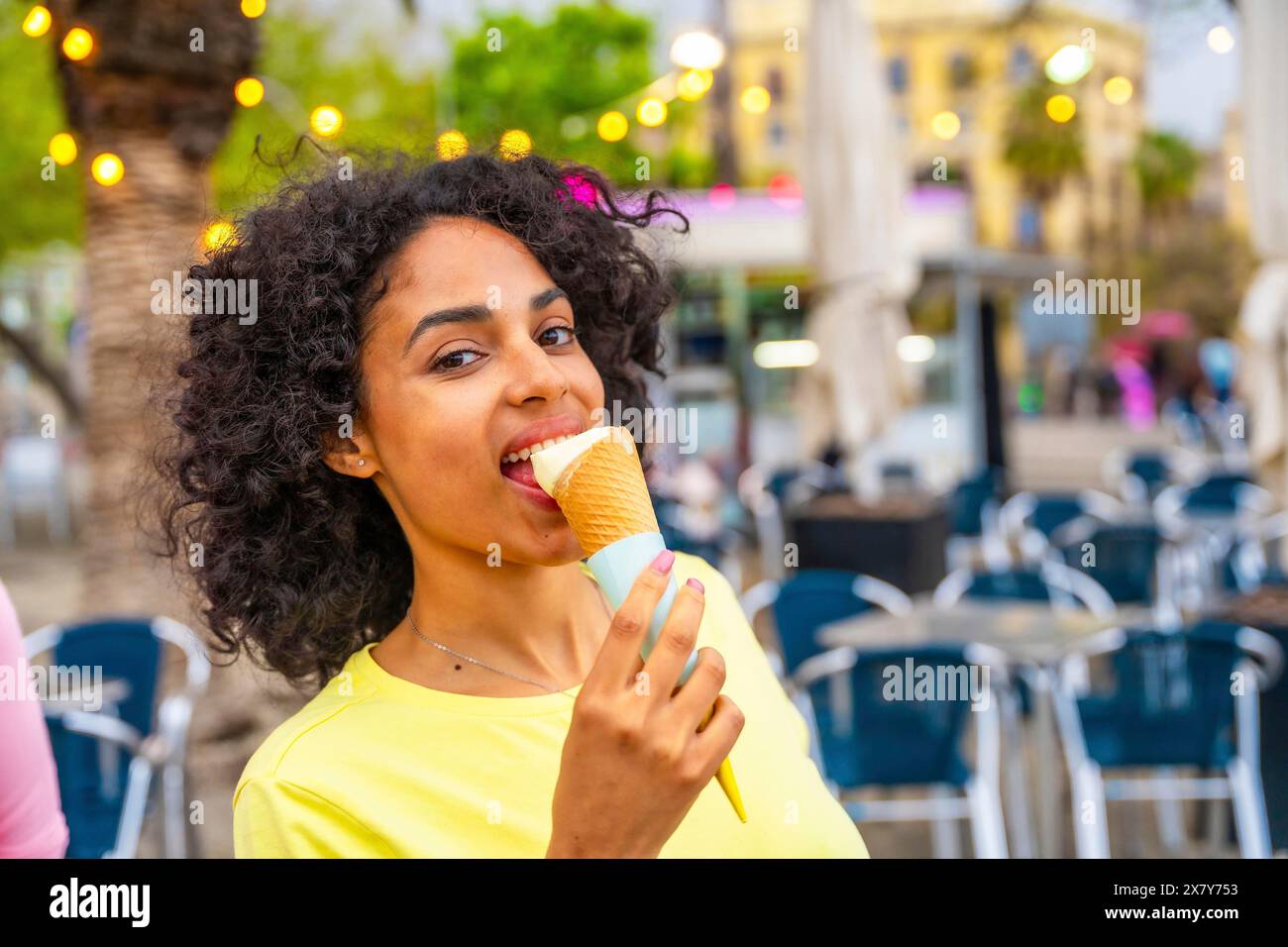 Ritratto ravvicinato di una donna latina che morde un cono di gelato in città Foto Stock