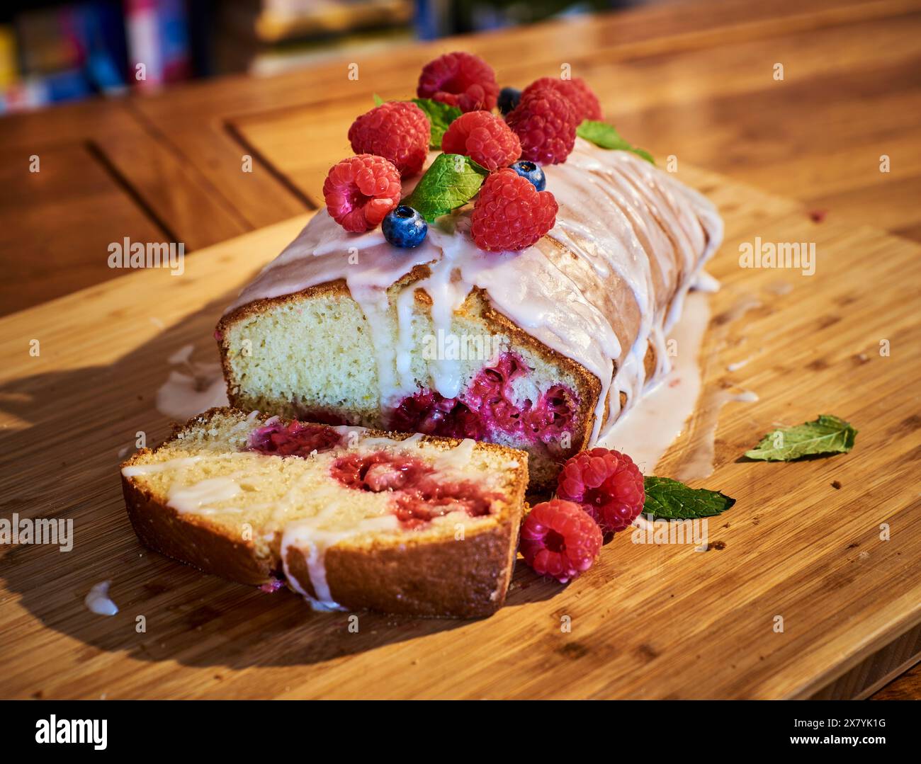 Torta di frutti di lampone o torta con dolce camice di zucchero fuso e lamponi selvatici su un tavolo di legno. Morbido plumcake caldo e ricoperto di zucchero cotto con frutti di bosco Foto Stock
