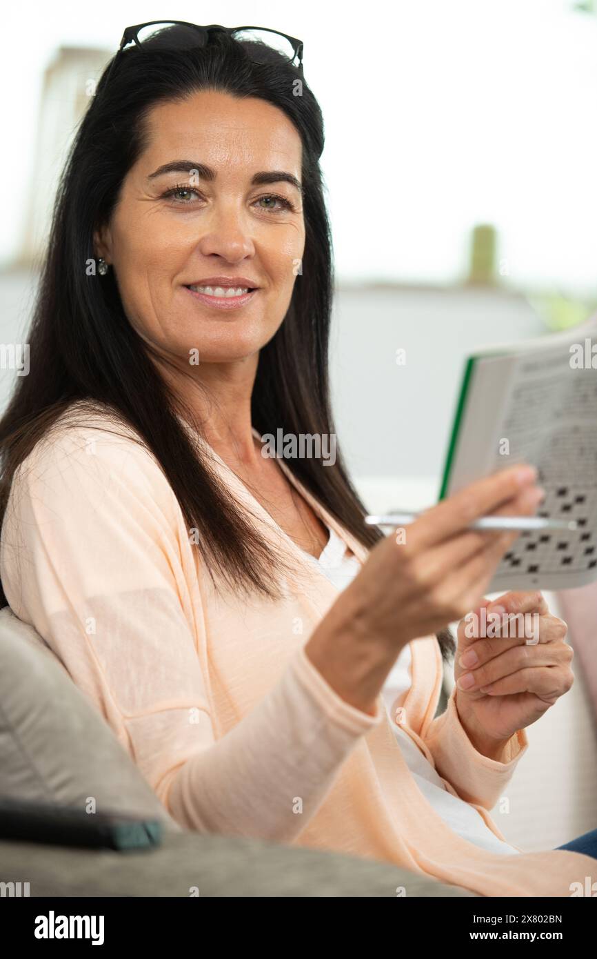 bella donna che fa parole incrociate in camera Foto Stock
