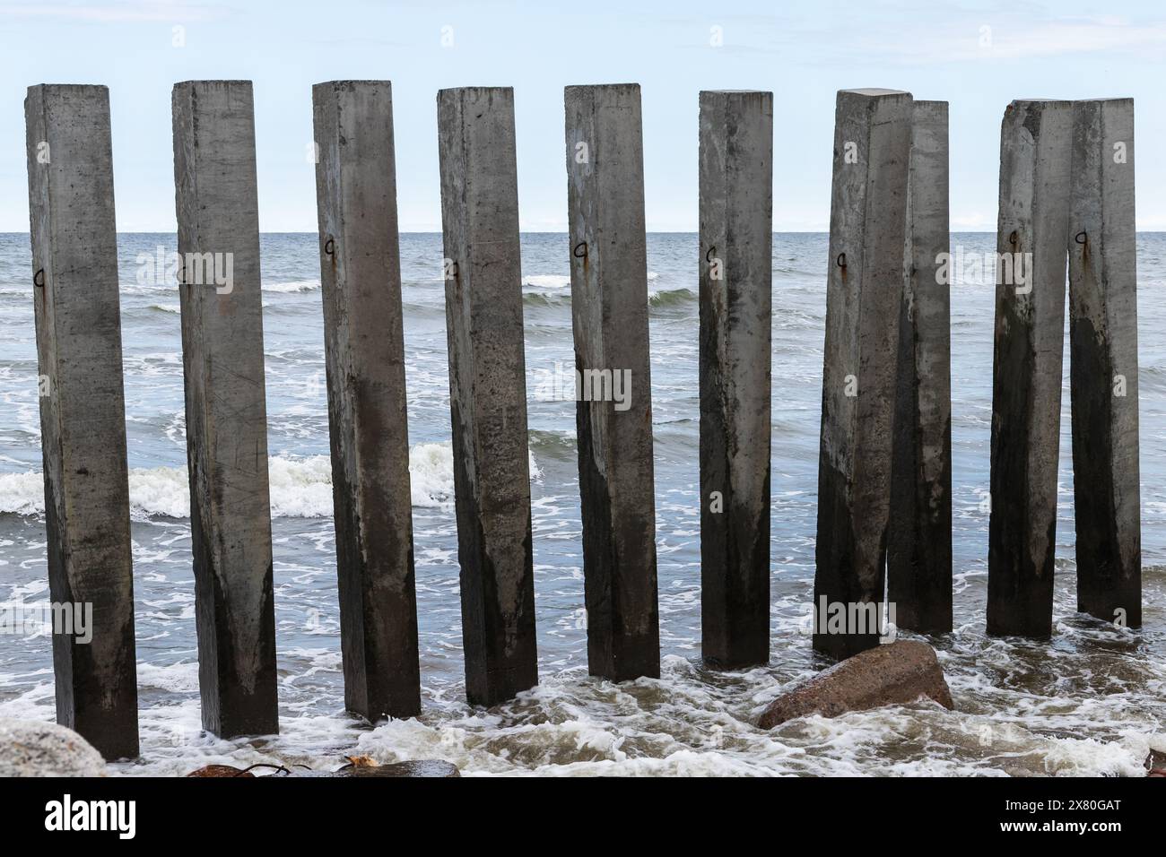Pilastri di cemento scuro come parte della struttura frangiflutti si trovano sulla costa del Mar Baltico. Svetlogorsk, Oblast' di Kaliningrad, Russia Foto Stock