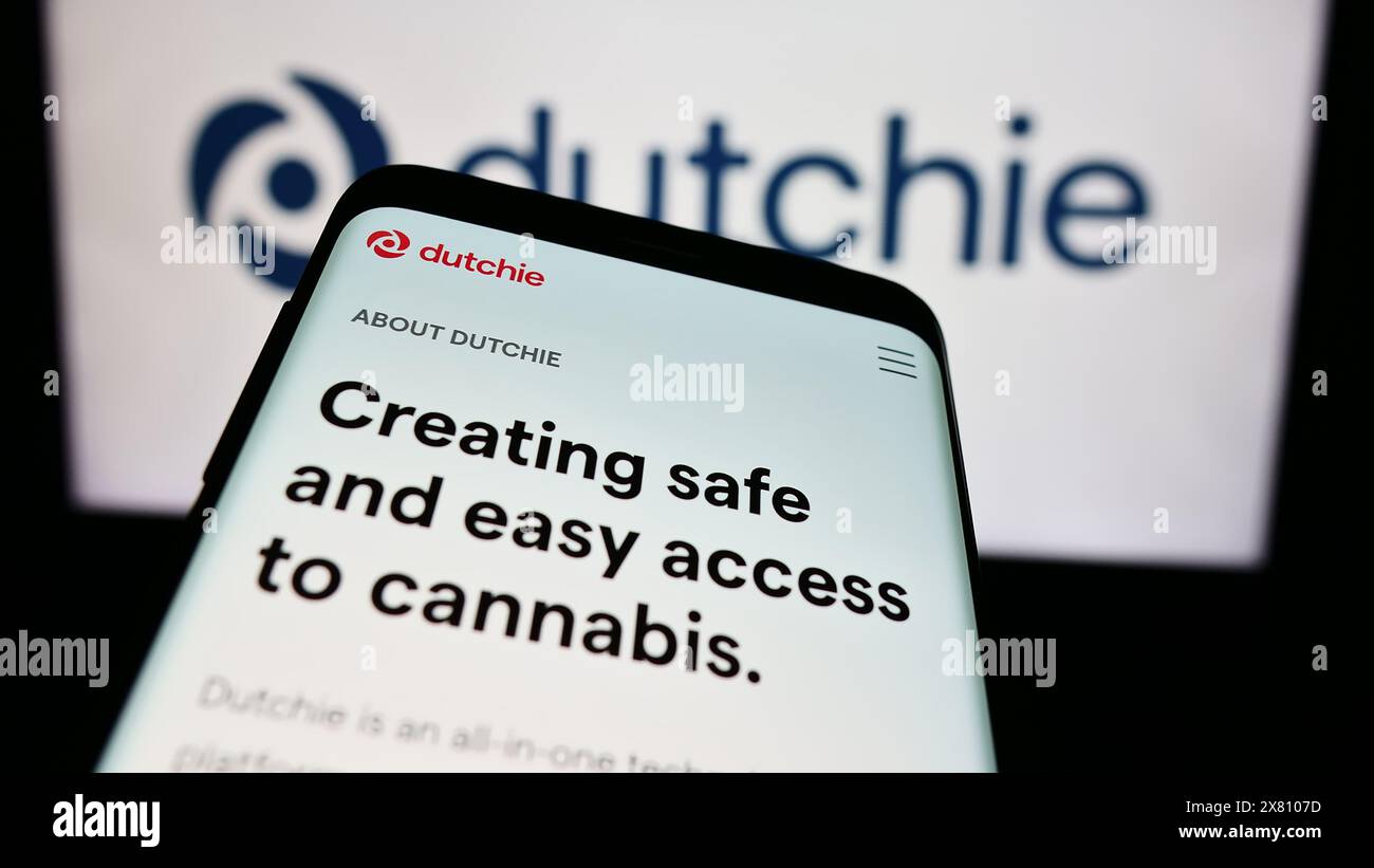 Telefono cellulare con sito web della società statunitense di cannabis Courier Plus Inc. (Dutchie) davanti al logo aziendale. Mettere a fuoco in alto a sinistra sul display del telefono. Foto Stock