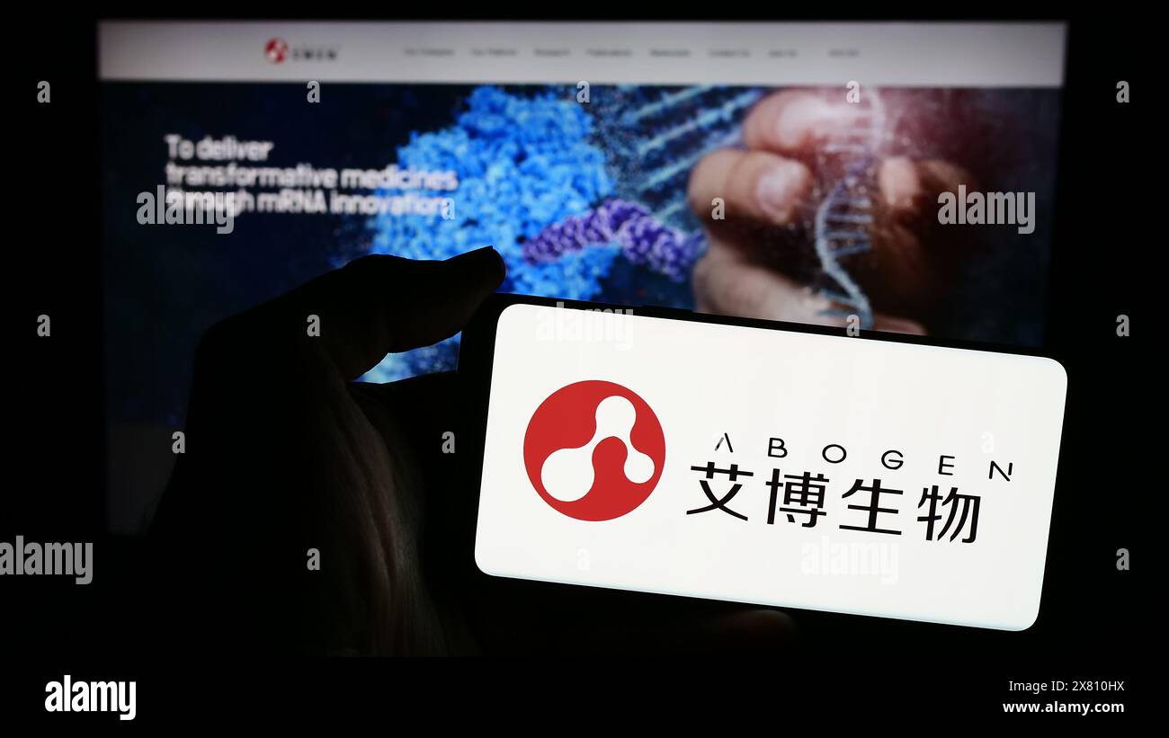 Persona che detiene un telefono cellulare con il logo della società cinese Suzhou Abogen Biosciences Co. Ltd. Di fronte alla pagina Web aziendale. Mettere a fuoco il display del telefono. Foto Stock