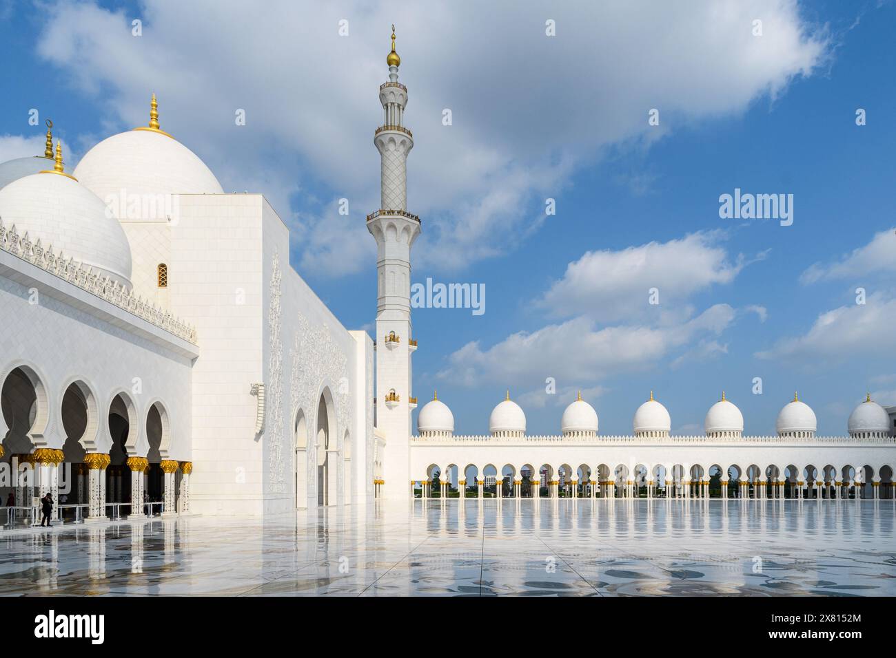 Eleganti archi e piscine riflettenti presso la serena grande Moschea Sheikh Zayed sotto un cielo blu. Foto Stock