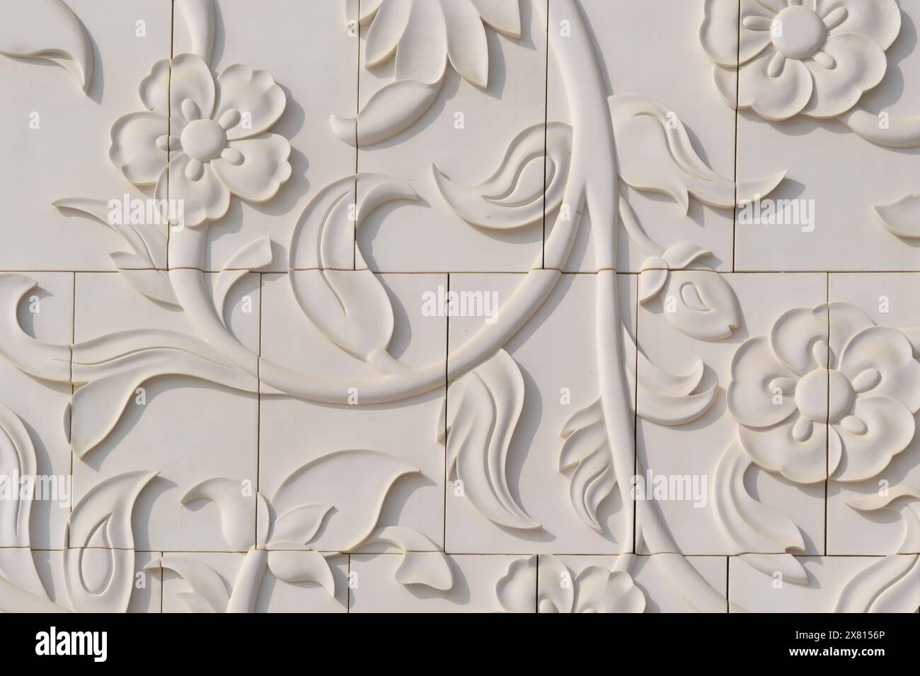 Intricate incisioni floreali adornano le pareti in marmo bianco della Moschea Sheikh Zayed ad Abu Dhabi, una testimonianza dell'artigianato. Frammento di muro in dec Foto Stock