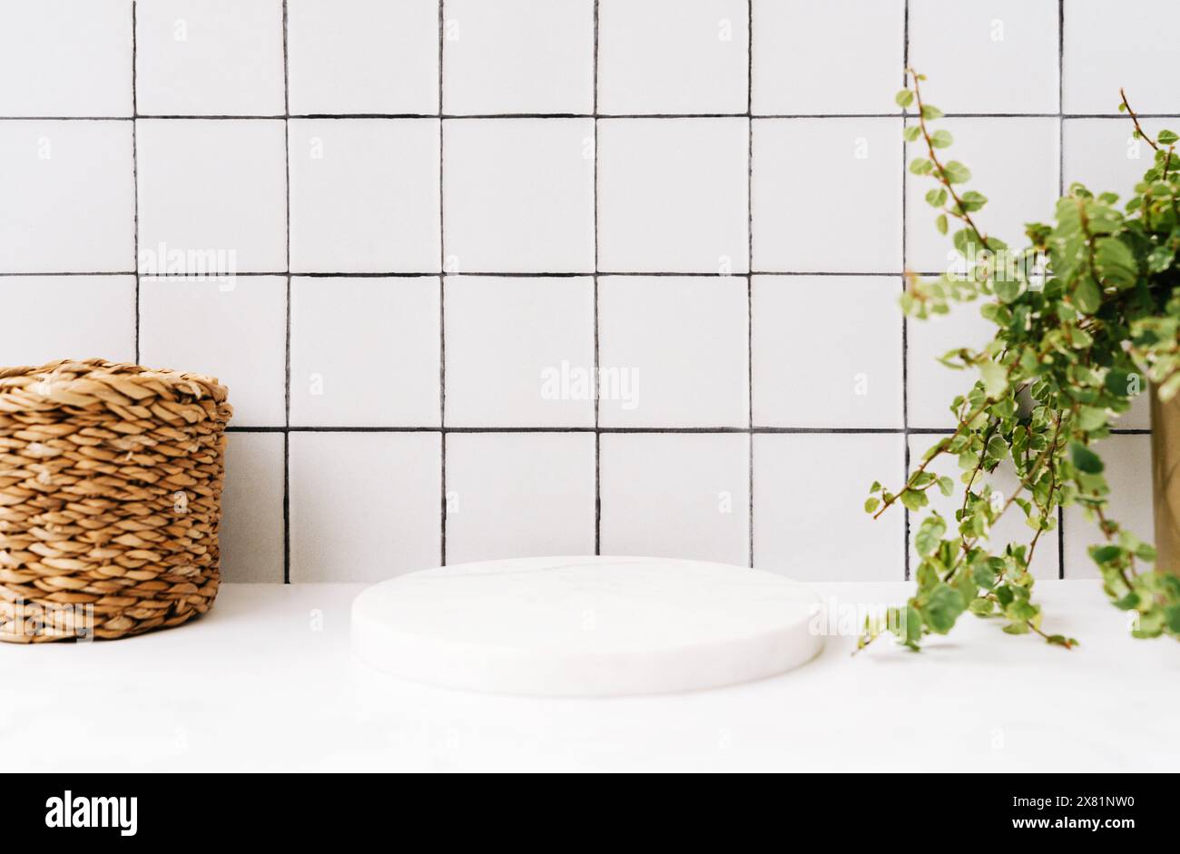 Podio rotondo bianco in marmo per prodotti da bagno in bagno vista frontale, paglia e piante verdi in pentola su mensola e piastrelle in marmo bianco. Copia spazio. Foto Stock