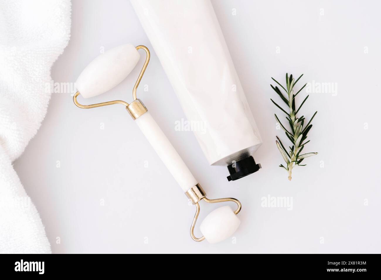 Primo piano di una provetta bianca senza etichetta e rullo facciale su sfondo bianco del tavolo in marmo. Concetto minimo di bottiglia di crema facciale, gel, mockup balsamo. Foto Stock