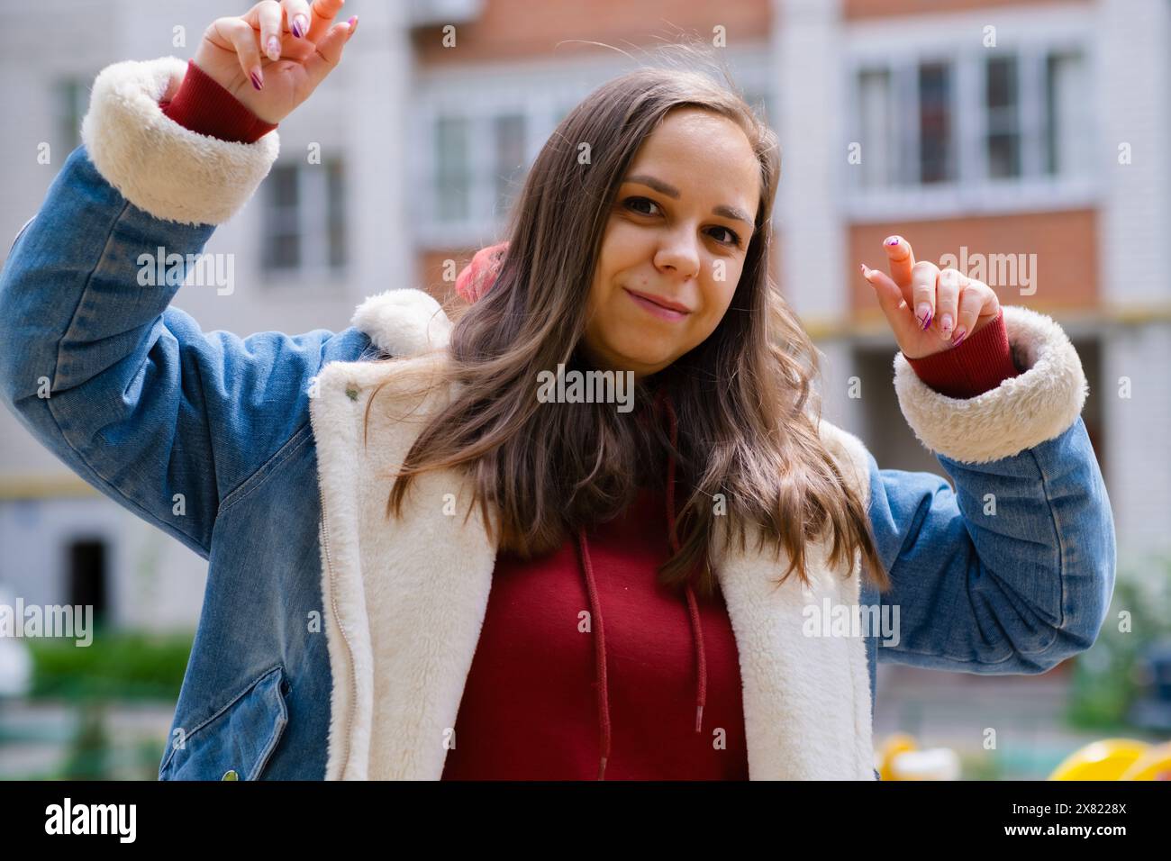 Una donna che indossa una camicia rossa danzerà energicamente, con le mani sollevate in aria in un vibrante spettacolo di movimento e gioia Foto Stock