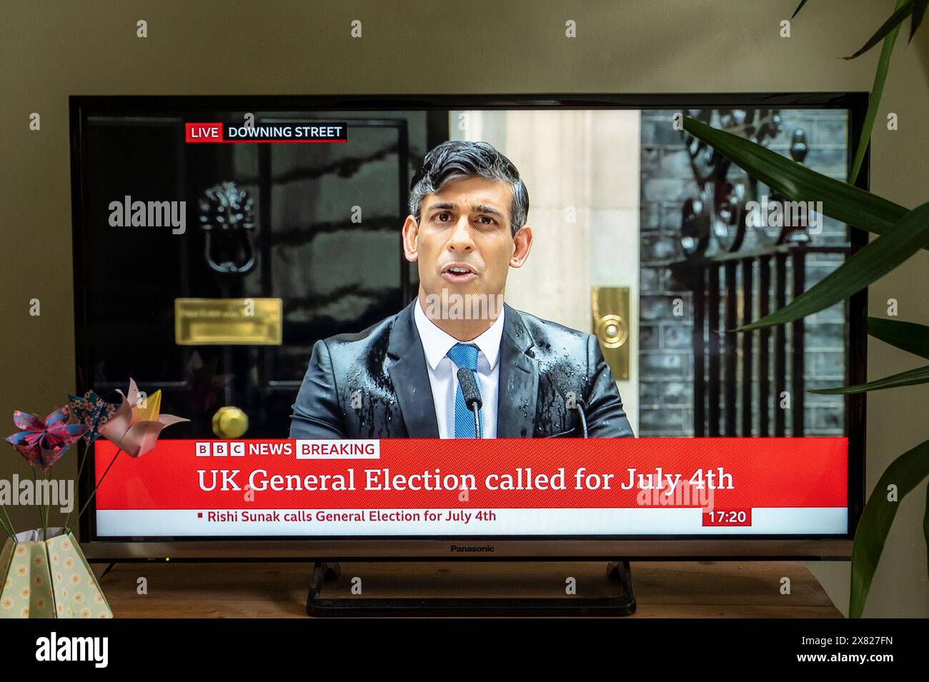 Il primo ministro britannico Rishi Sunak annuncia le elezioni generali per il 4 luglio 2024 su BBC TV News, mentre si immerge di pioggia. Downing Street, Londra. Foto Stock