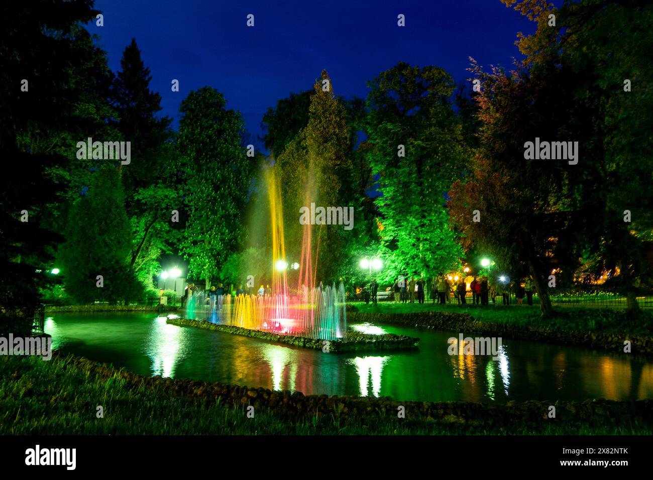 Bellissimi e colorati acquedotti di notte a Polanica-Zdrój, in Polonia, che si riflettono in un piccolo lago con un lungo tempo di esposizione e un effetto di sfocatura del movimento Foto Stock