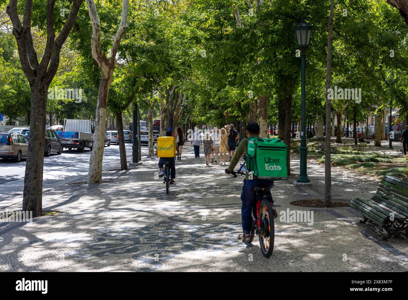 Lisboa, Portogallo - 18.09.2023: Corrieri per i servizi di consegna Uber Eats e Glovo in sella a una bicicletta attraverso Liberty Avenue (Avenida da Liberdade) in t Foto Stock