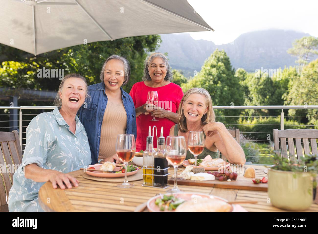 Diverse amiche anziane che si godono il pasto all'aperto, ridono insieme Foto Stock