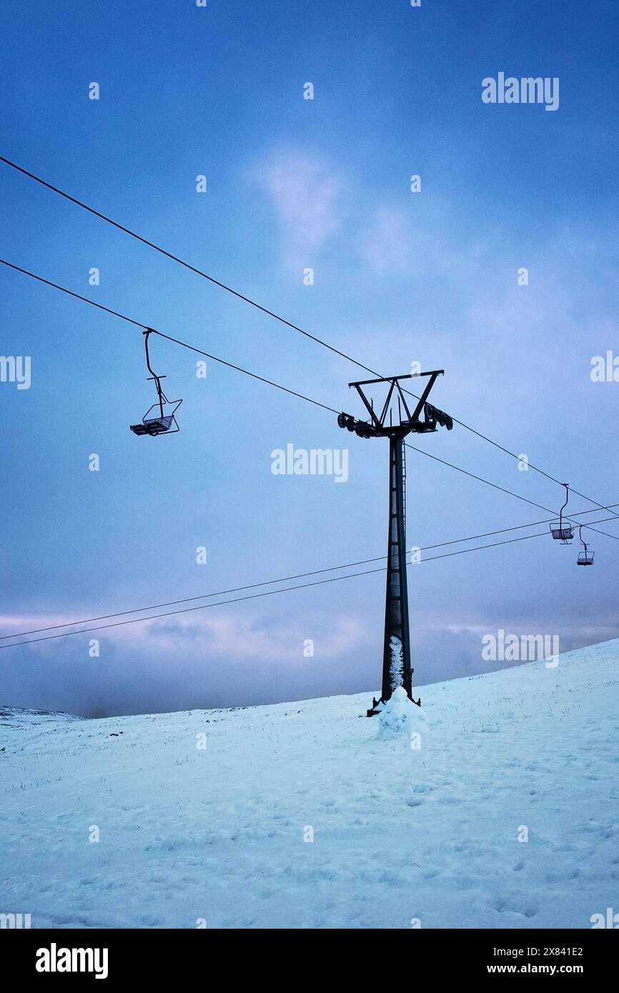 Skilift sulla neve con un cielo azzurro e rosa alle spalle Foto Stock