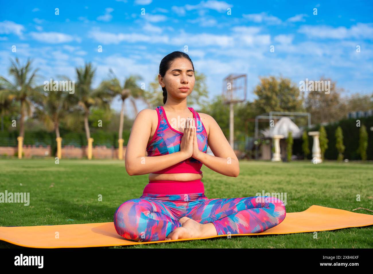 Adatta giovane donna indiana che pratica surya namaskar yoga posa in giardino. esercizio fisico, allenamento, meditazione, benessere, concetto di salute mentale. Foto Stock