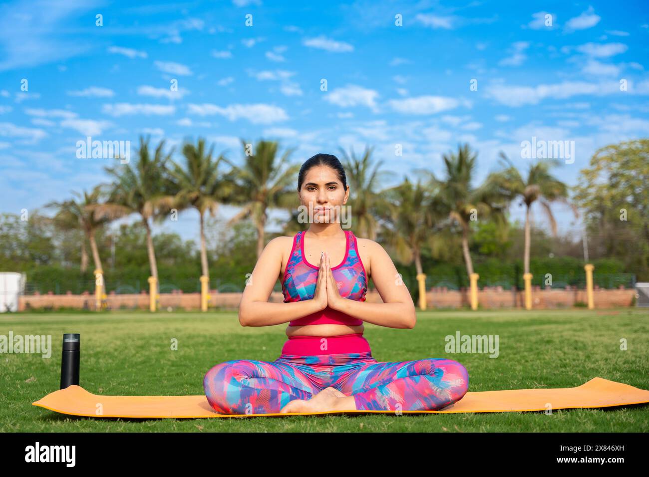 Adatta giovane donna indiana che pratica surya namaskar yoga posa in giardino. esercizio fisico, allenamento, meditazione, benessere, concetto di salute mentale. Foto Stock