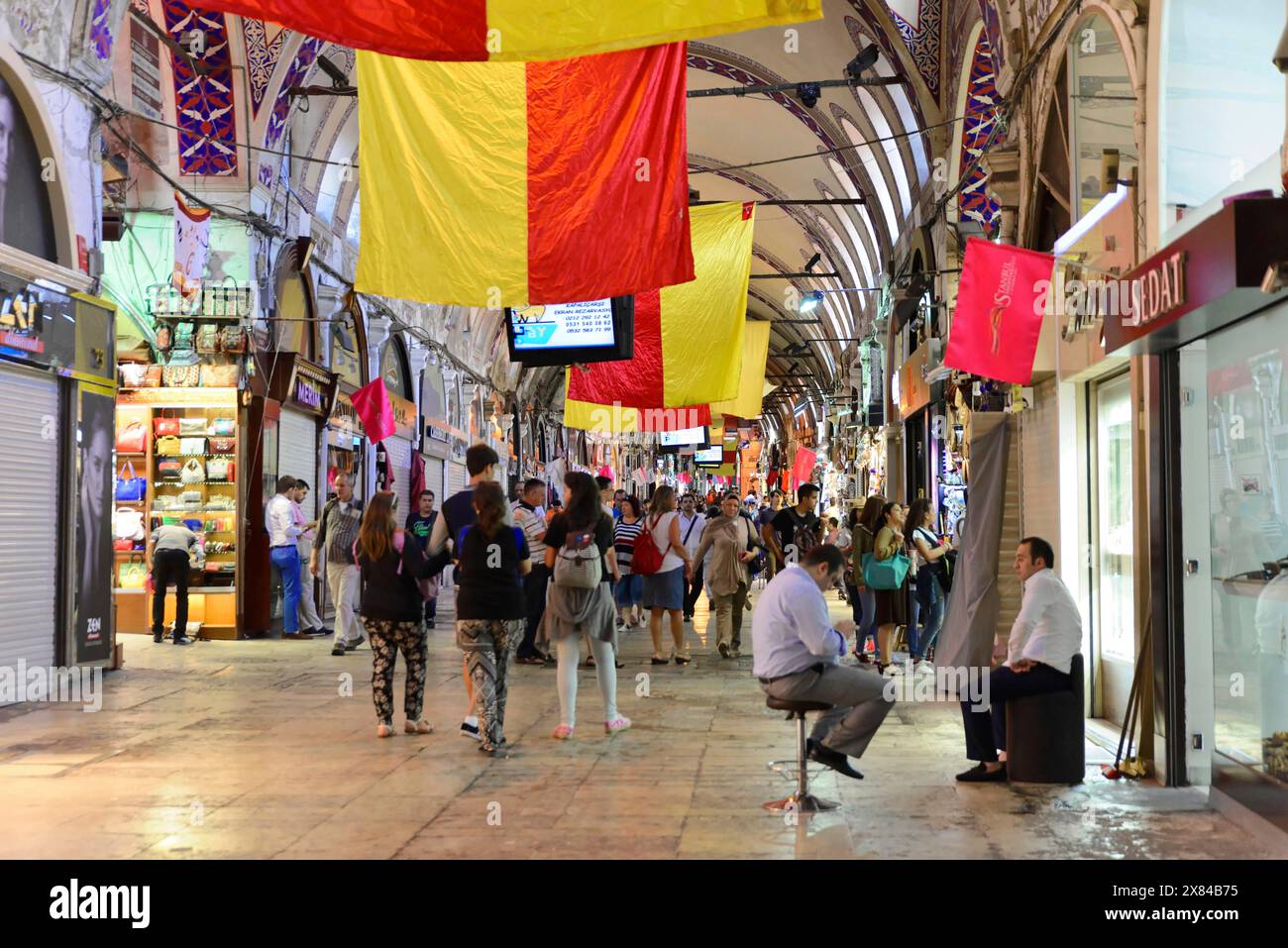 Grand Bazaar, Istanbul, Turchia, Asia, vivace bazar in serata, illuminato e decorato con bandiere rosse e gialle, folle di persone che fanno shopping Foto Stock