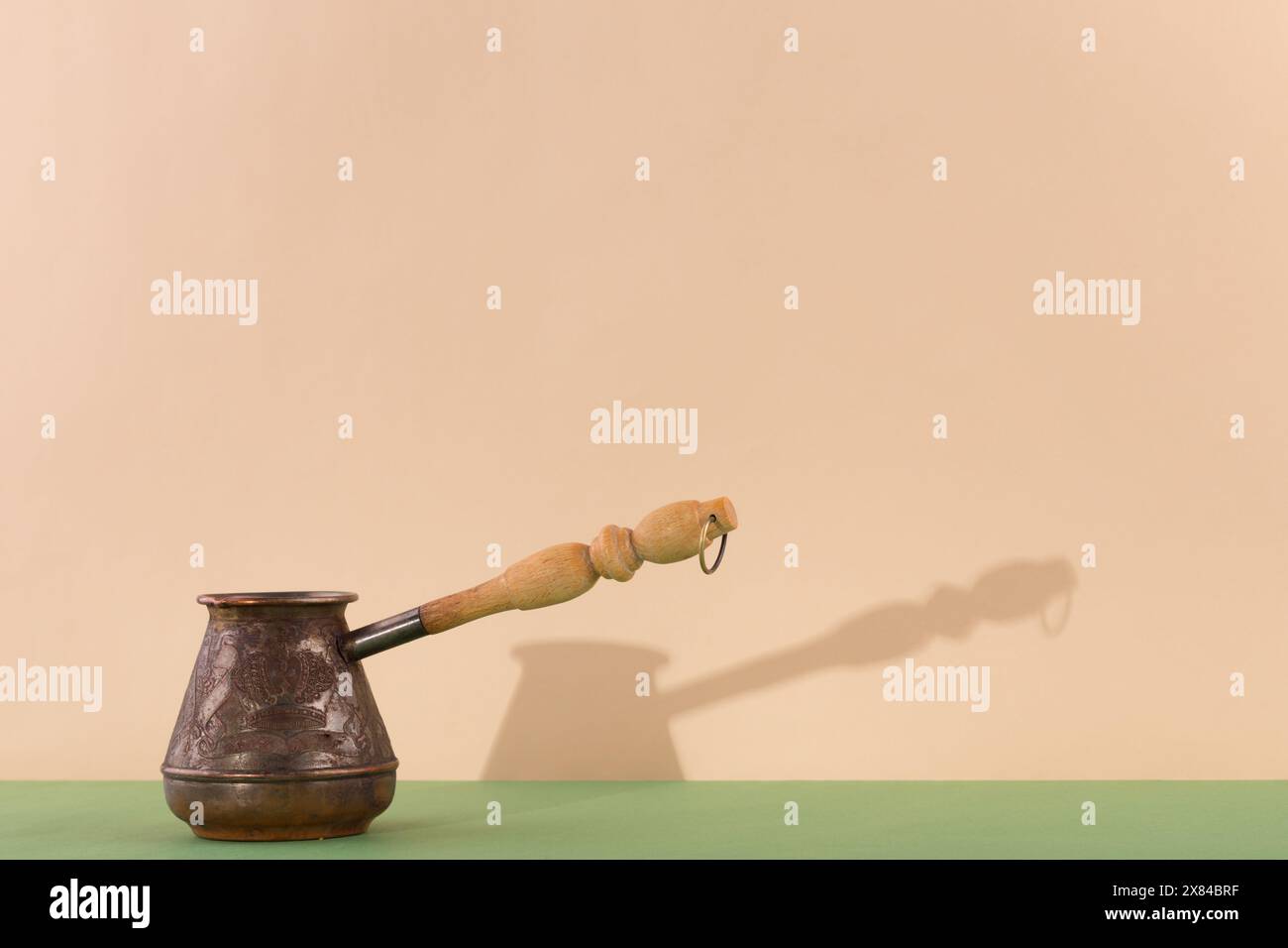 Ibrik di ottone con goffratura e ombra. Concetto di caffetteria e ristorante. Il colore dello sfondo è lo champagne della vela. Foto Stock