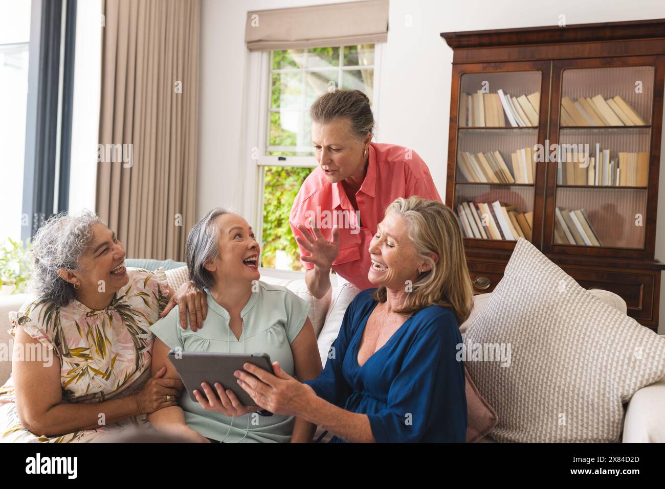 Diverse amiche anziane sedute a casa, un tablet in mano Foto Stock