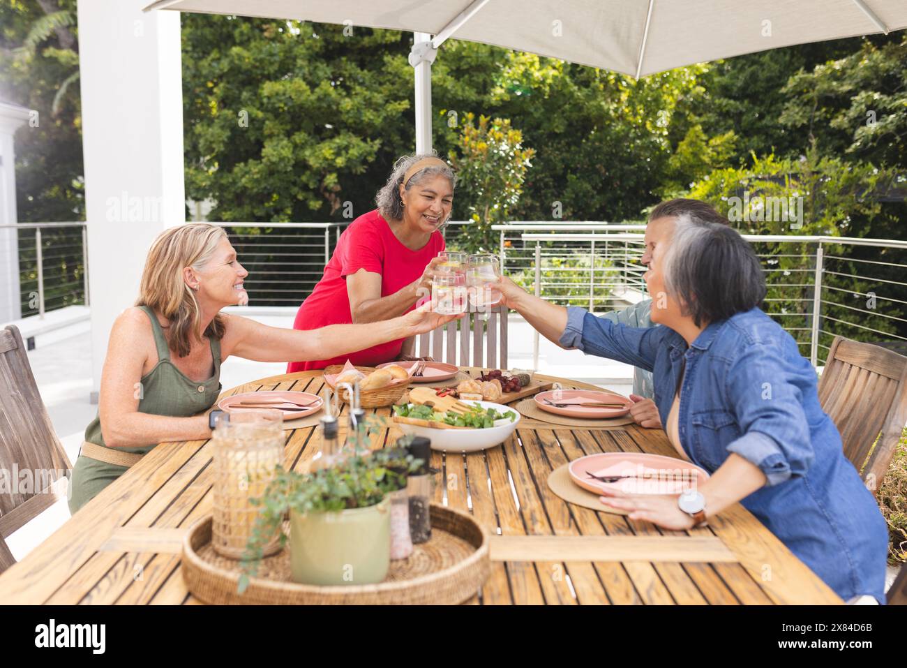 Diverse amiche anziane che tostano i bicchieri all'aperto Foto Stock