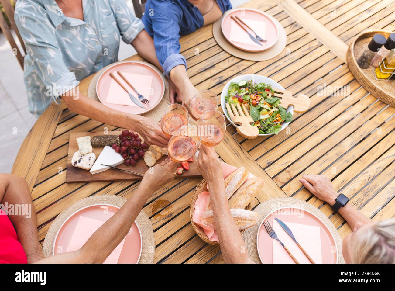 Diverse amiche anziane brindano con vino all'aperto e mangiano Foto Stock