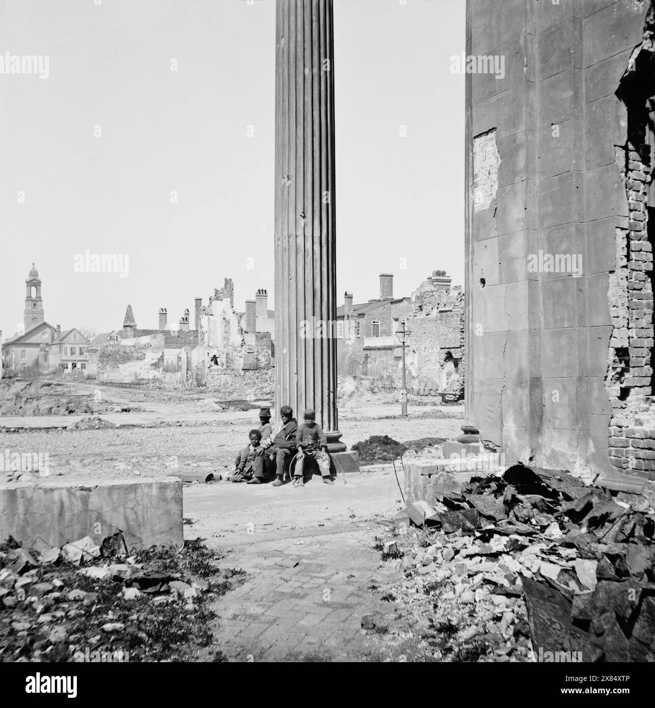 Charleston, S.C. veduta degli edifici in rovina attraverso il portico della Chiesa circolare (150 Meeting Street). Aprile 1865. Fotografo: George N. Barnard. Quattro bambini afroamericani siedono alla base di una grande colonna greca. Fotografie della Marina Federale e spedizioni in mare contro la costa atlantica della Confederazione -- in particolare Charleston, S.C. 1863-1865. Il successo del generale Gillmore a Fort Pulaski gli valse la condotta di un'impresa molto più difficile: La riduzione delle difese del porto di Charleston, con l'aiuto di uno squadrone al comando del Rear Adm. John A. Dahlgren. Le operazioni implorano Foto Stock